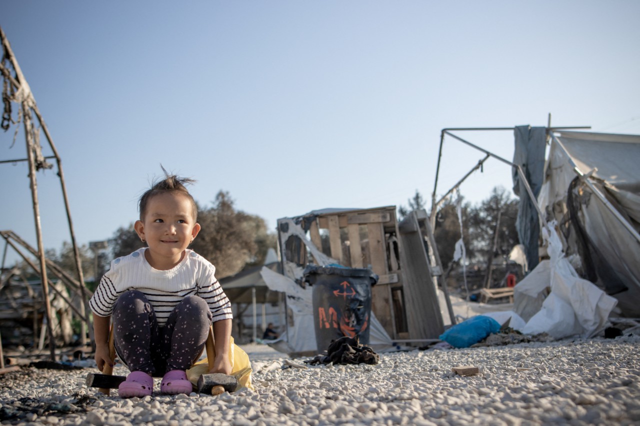 Menina brinca nos escombros do campo de refugiados de Moria, na ilha de Lebos (Grécia), que sofreu incêndio em 2020. É o maior campo em toda a Europa - AFP