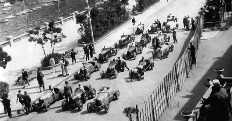Imagem monocromática de 1929 com os carros de corrida alinhados antes do início da prova.