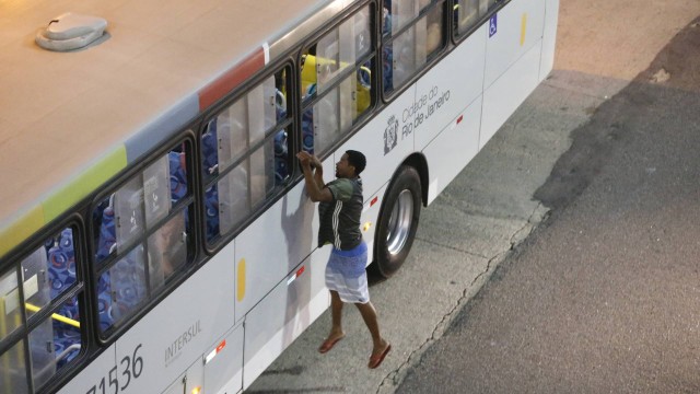 Cena comum nas grandes metrópoles: assaltante tenta alcançar celular na mão de passageiro dentro do ônibus
