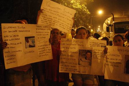 Moradores exibem cartazes com fotos dos presos