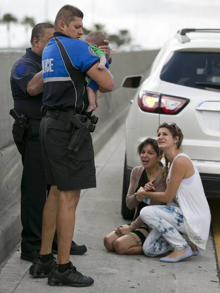 Um policial ajuda a resgatar o bebê que recebeu primeiros-socorros da tia