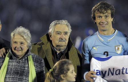 Mujica entrea sua mulher, Lucia Topolansky, e o capitão da seleção uruguaia, Diego Lugano, antes de amistoso em Montevidéu