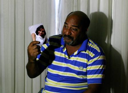 Ironildo Motta chora enquanto segura uma foto da filha morta