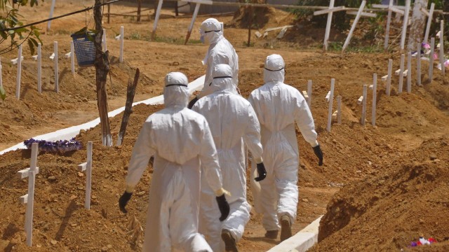 Agentes de saúde caminham em cemitério destinado a vítimas do Ebola na Libéria