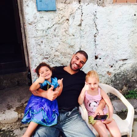 Adriano Imperador posa abraçado com duas garotinhas na Vila Cruzeiro