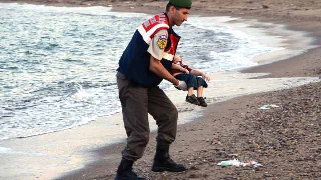 Policial retira corpo de menino sírio de 3 anos, que se afogou durante fuga da guerra em seu país.