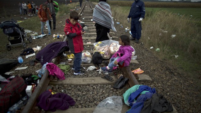 Refugiados sírios descansam em trilho de trem depois de atravessarem fronteira entre Sérvia e Hungria