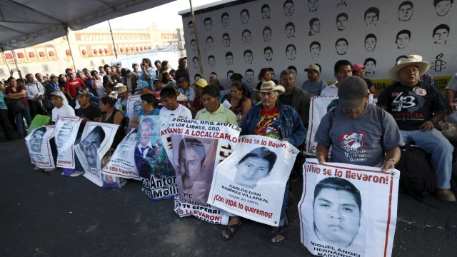 Familiares seguram fotos de alguns dos estudantes desaparecidos sob uma tenda montada em frente à Catedral da Cidade do México