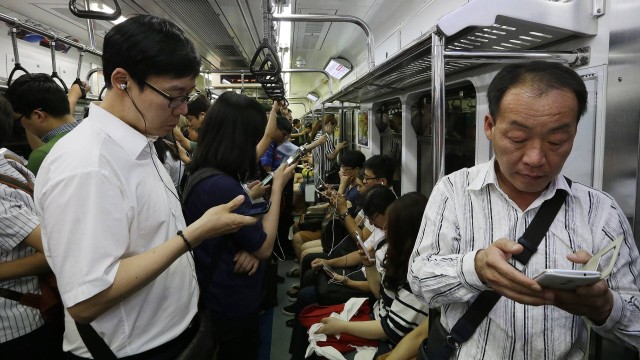Passageiros do metrô de Seul, na Coreia do Sul, usam dispositivos eletrônicos durante a viagem