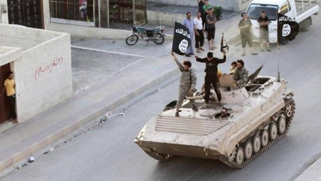 Militantes do Estado Islâmico carregam bandeira da organização durante desfile militar nas ruas de Raqqa em junho de 2014