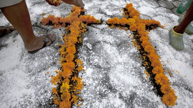 A woman makes a couple of crosses out of flowers at the exact place where a mob beat, killed and burned two pollsters who were conducting a survey, in front of the Municipal Palace in Ajalpan, Puebla, Mexico, Wednesday, October 21, 2015. Police had tried