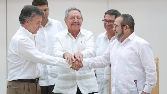 Santos (à esquerda) aperta a mão de Timochenko, líder das Farc, observado por Raúl Castro (ao centro): promessa de paz
