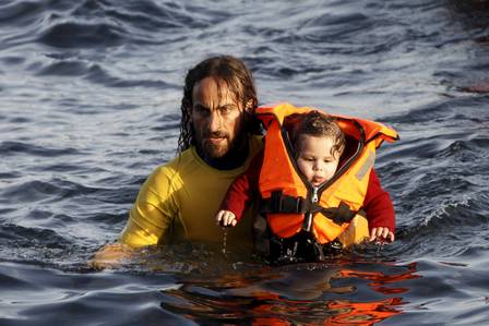 O voluntário carrega o bebê no Mar Egeu