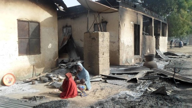 Uma mulher vela o marido após o ataque do Bojo Haram na Nigéria