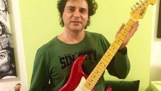 O roqueiro Roberto Frejat segura uma das duas guitarras doadas para serem leiloadas pela ONG Paraíso dos Focinhos