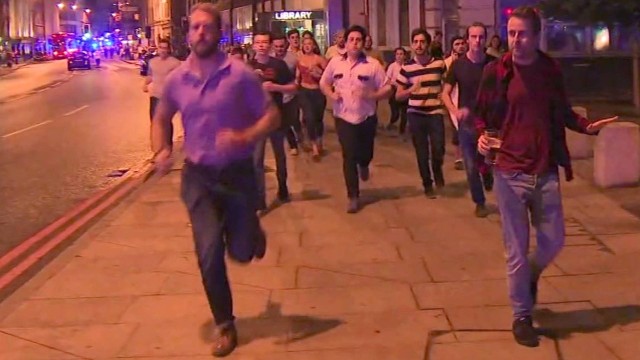 Homem de vermelho (à direita) caminha após atentado