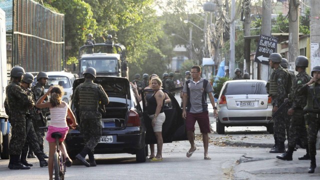 Na Favela do Muquiço, militares revistam carro e moradores.