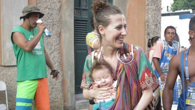 Mãe leva o filho bebê no sling durante desfile do bloco Céu na Terra