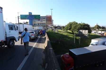 Com o trânsito totalmente parado na Avenida Brasil, passageiros descem de ônibus e caminham pela via