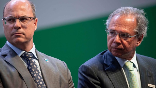 Rio de Janeiro Governor Wilson Witzel (L) and Brazil's Economy Minister Paulo Guedes (R) attend the ceremony where economist Roberto Castello Branco took office as president of the Brazilian oil company Petrobras at the company's headquarters in Rio de Janeiro, Brazil on January 3, 2019. (Photo by Mauro Pimentel / AFP)