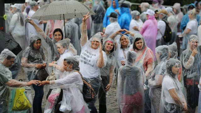 Para aguentar a chuva, fãs compram sombrinhas e capas de chuva