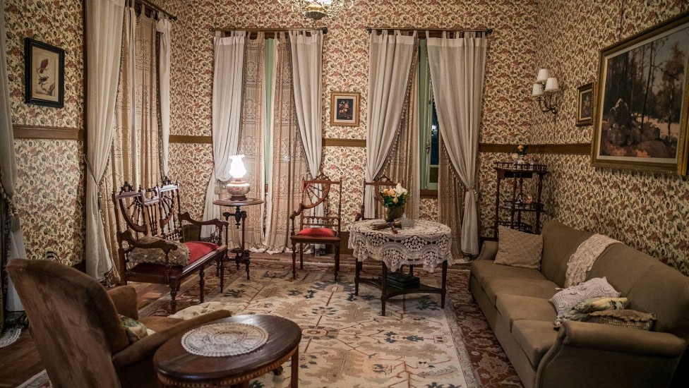 A sala de Lola é o local de reunião de família Lemos; o ambiente tem papel de parede, cortinas, tapete e diversos itens de decoração que demonstram o gosto de...