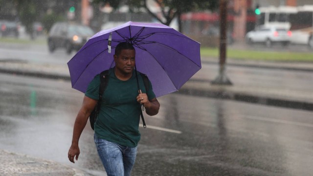 Homem caminha sob a chuva na Avenida Presidente Vargas