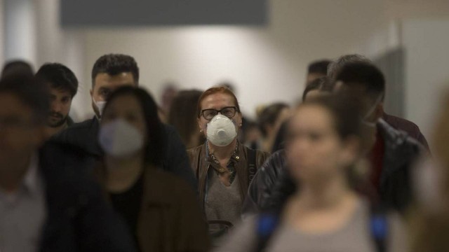 Passageiros usam máscaras no desembarque do aeroporto internacional de Guarulhos: medo de contaminação está levando ao cancelamento de viagens