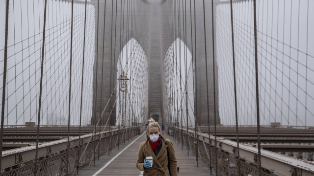 Jovem vestindo máscara atravessa a Ponte do Brooklyn, em Nova York