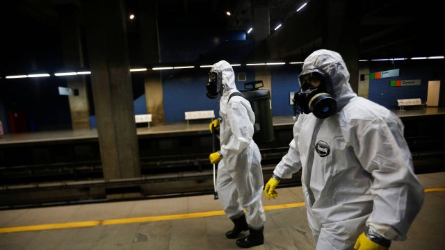 Membros das forças armadas usam roupas de proteção contra o coronavírus para desinfectar uma estação de metrô em Brasília.
