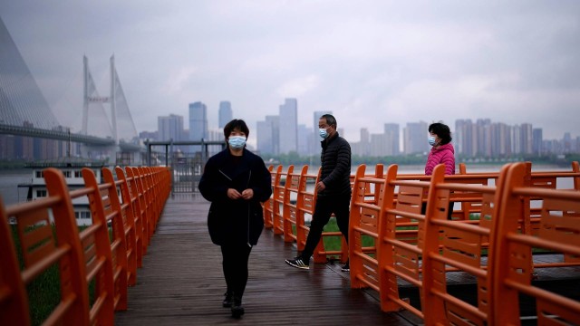 Pessoas andam de máscara pela cidade de Wuhan, capital da província de Hubei, onde a doença começou em dezembro de 2019.