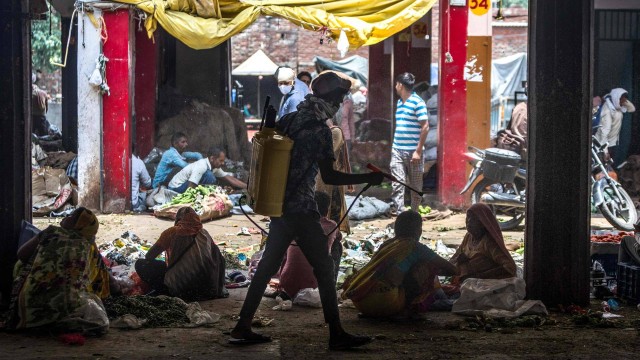 Trabalhador usa desinfetante em feira de alimentos para conter avanço do coronavírus, em Nova Délhi, na Índia