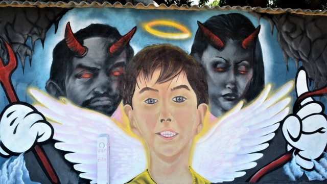 Em mural, Henry aparece como anjo e Dr. Jairinho e a mãe do menino, Monique, são retratados como demônios