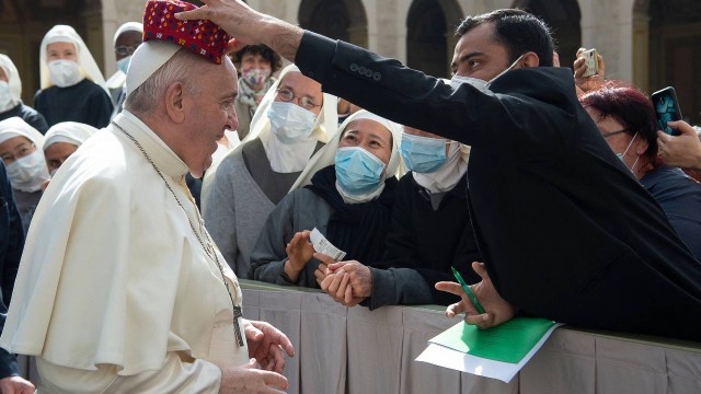 Fiel coloca um chapéu das Filipinas na cabeça do Papa Francisco no retorno da audiência geral semanal ao ar livre com o público