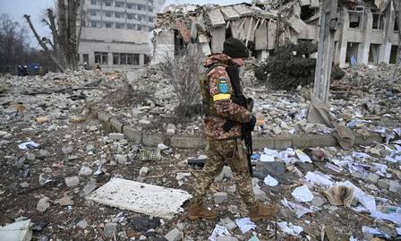 Militar ucraniano caminha perto de uma escola destruída por bombardeios russos em Zhytomyr, Ucrânia