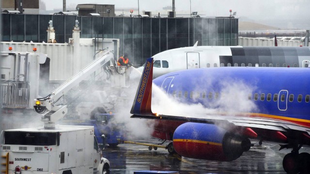 Funcionários de empresa aérea preparam avião para decolagem do aeroporto de LaGuardia, enquanto nevasca continua