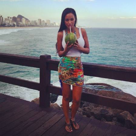 Fanny posa bebendo água de coco no deck da Praia do Leblon